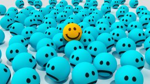 one happy face among many sad ones emojis