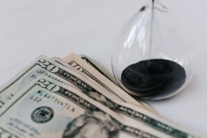 close up photo of hourglass and american paper bills