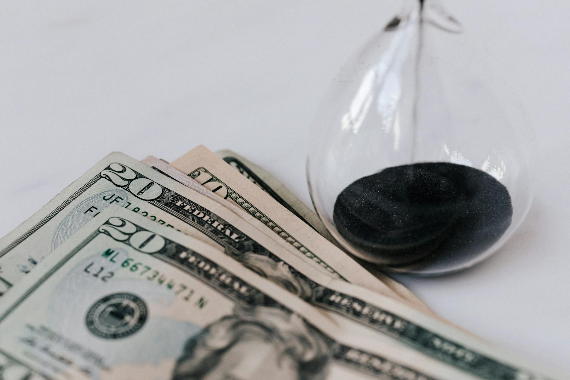 close up photo of hourglass and american paper bills